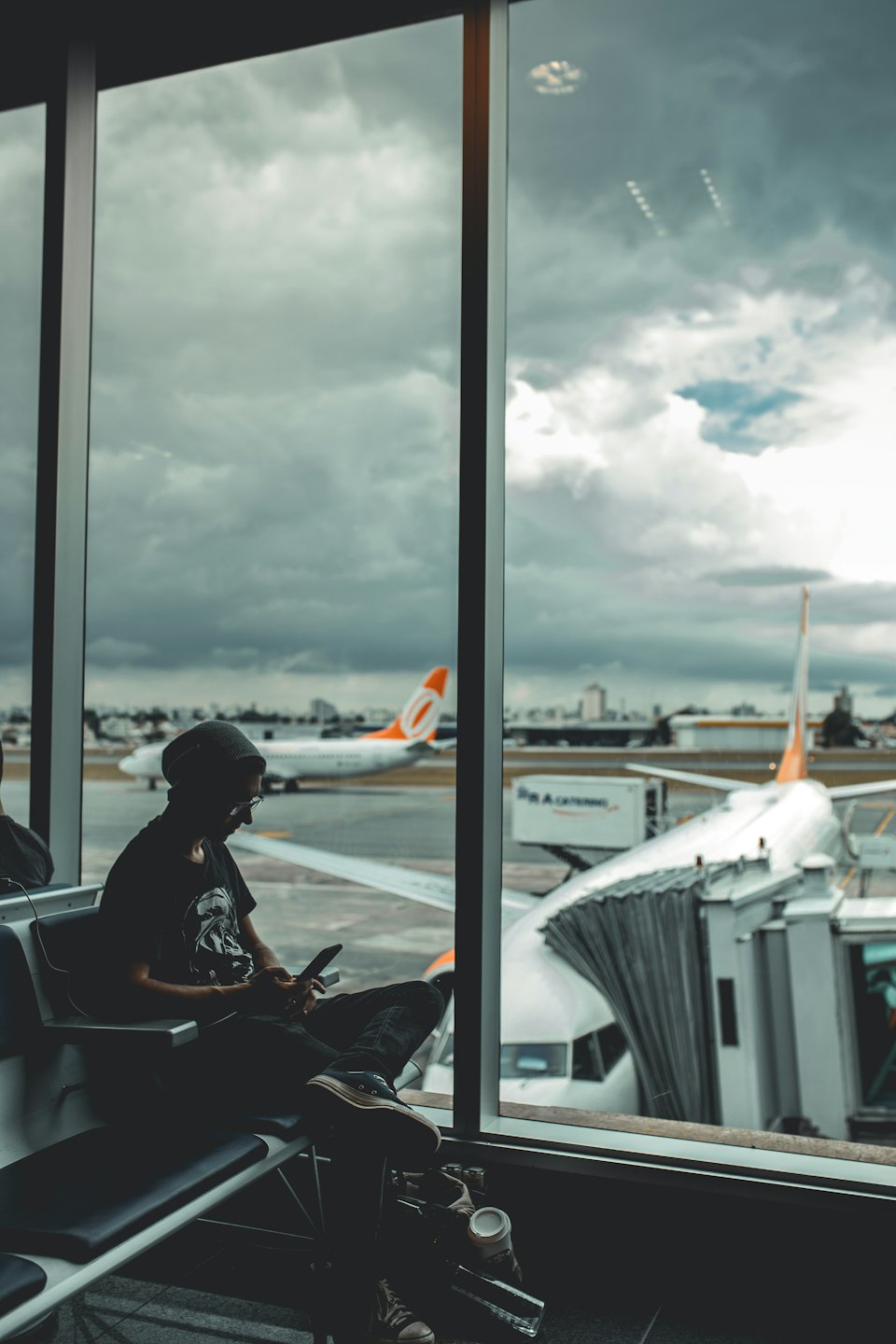 Traveler sitting on a terminal bench looking at their phone.